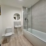 Modern bathroom with bathtub and round mirror.