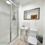 Modern bathroom with shower, sink, and toilet.