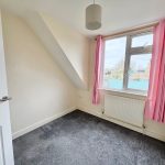 Small empty room with pink curtains and window view.