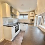 Modern kitchen with white cabinets and black countertops.