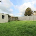 Spacious garden with grassy lawn and wooden fence.