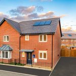 Modern brick house with solar panels across roof.