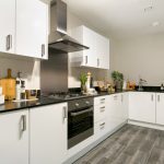 Modern kitchen with white cabinets and black countertop.
