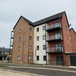 Modern apartment building with balconies and parking.