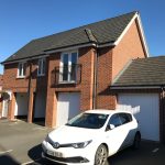 Brick house with garage and parked white car.
