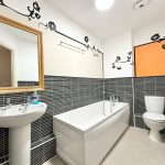 Modern bathroom with black tiles and floral decor.