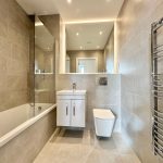 Modern bathroom with tub, vanity, and towel rail.