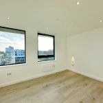 Bright empty room with large windows and wooden floor.