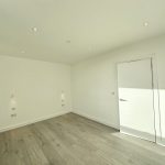 Minimalist empty room with wooden floor and white walls.