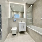 Modern bathroom with grey tiles and glass shower.