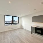 Modern flat with large window and sleek kitchen.
