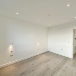 Empty room with wooden flooring and white walls.