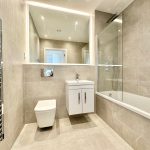 Modern bathroom with bathtub and large mirror.