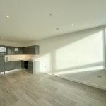 Modern kitchen with large window and wooden flooring.