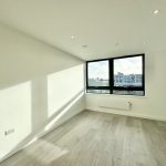 Empty modern room with large window and wooden floor.