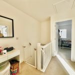 Bright landing with mirror and open doorway.