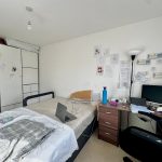 Organised bedroom with desk, bed, and wall drawings.