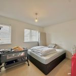 Bright bedroom with bed, cot, and suitcase