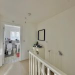 White interior hallway leading to a bathroom.
