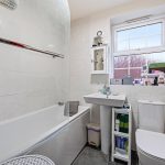 Modern bathroom with sink, bath, and window.