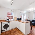 Modern kitchen and living area with wooden flooring.