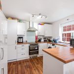 Modern kitchen with wooden countertops and white cabinets.