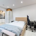 Cosy bedroom with desk and kitchen view.