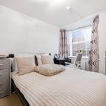 Bright bedroom with double bed and office corner.