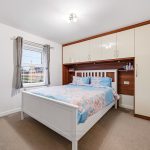 Modern bedroom with double bed and fitted cupboards.