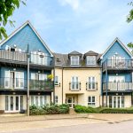Modern residential building with balconies and greenery.