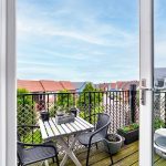 Balcony view with table, chairs, and houses.