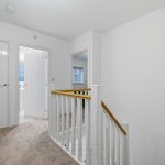 Modern hallway with white doors and carpeted floor.