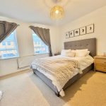 Modern bedroom with double bed, art, and neutral decor.