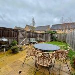 Garden with patio furniture and barbecue on cloudy day.