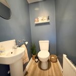 Small modern bathroom with blue walls and wooden floor.