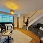 Living room with sofa, desk, and staircase.