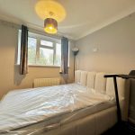 Modern bedroom with bed, treadmill, and window view.
