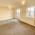 Spacious carpeted room with natural light.