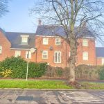 Red brick house with tree in front garden.