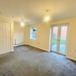Empty room with carpet, two windows, and door.