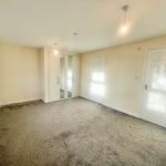 Spacious empty bedroom with beige walls, carpet floor.