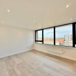 Bright empty room with large windows and wooden floor.