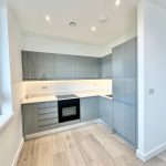 Modern kitchen with glossy cabinets and wooden flooring.