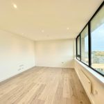 Spacious, bright room with large windows and wooden floor.