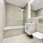 Modern bathroom with bathtub and vanity unit.