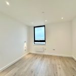 Empty room with wooden floor and large window.