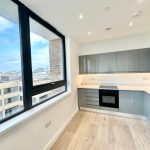 Modern kitchen with large window and grey cabinets.