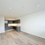 Modern kitchen with wooden floor and grey cabinets.