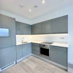 Modern grey kitchen with appliances and white counters.