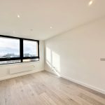 Bright empty room with large window and wood floor.